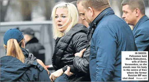  ?? Picture: AFP ?? IN SHOCK: Policemen hold Maria Maksakova, wife of Denis Voronenkov, as she stands near his body in the centre of Kiev where the former Russian MP was shot dead