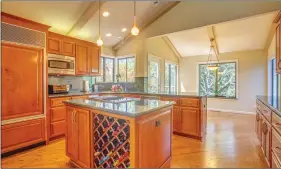  ??  ?? The well-appointed kitchen features custom cabinetry, pull out shelving, granite counters and backsplash, wine storage, island and breakfast bar. The formal dining room is spacious for large gatherings and the adjacent step down living room features a...