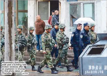  ?? REUTERS ?? Paramilita­ry policemen walk past a building with broken windows after an explosion in Urumqi in this photo taken on Thursday.