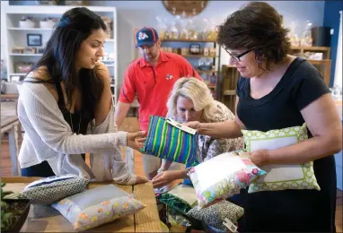  ?? RECORDER PHOTOS BY CHIEKO HARA ?? Ashley Bird, left, donates handmade pillows to Diane Chrisman of Fresno’s Community Regional Medical Center, right, to make handprint pillows for surviving family members of patients who pass away Saturday, Oct. 13 at Stafford’s Chocolates in downtown Portervill­e. Bird received a similar pillow when her sister Kati Giannetto passed away in 2012 and donated the pillows in her memory.