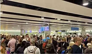  ?? ?? In this screenshot from an AP video, hoardes of travellers are seen stuck at Heathrow airport a er e-gates failed on Tuesday