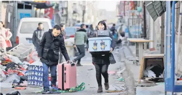  ??  ?? A couple leave with their belongings after they were required to move out due to a citywide fire safety inspection prompted by a deadly fire in an apartment block, at Xinjiancun in Daxing district, in Beijing. — Reuters photo