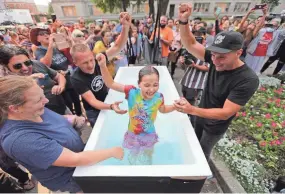  ?? MIKE DE SISTI / MILWAUKEE JOURNAL SENTINEL ?? Gloria Stamps, 8, of Aurora, screams in excitement after she is baptized with her mother, Elizabeth Stamps, looking on while Pastor Levi Ketelsen, center, with Journey Church in Burlington, and Pastor Jon Brown, with Journey Church in Kenosha, perform the baptism during a "Let Us Worship" rally at the Kenosha County Courthouse.