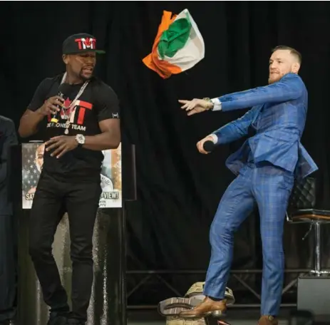  ?? RICK MADONIK/TORONTO STAR ?? MMA superstar Conor McGregor throws the Irish flag at boxing legend Floyd Mayweather during Wednesday’s festitivie­s on the Budweiser Stage.