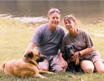  ?? AMY HUNTER/AP ?? John and Amy Hunter with their dogs, Apollo, left, and Rubi, a black Labrador retriever, in Brown County State Park south of their home in Indianapol­is, Ind. The couple is childless by choice and Amy is a stay-at-home pet mom.