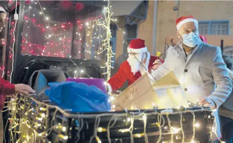  ?? MAYAALLERU­ZZO/AP ?? Volunteers from a Catholic men’s group distribute presents to children on Christmas Eve from the back of a motorized rickshaw in the Christian Quarter of the Old City of Jerusalem.