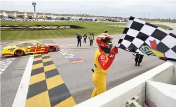  ?? GETTY IMAGES ?? Joey Logano shows off the checkered flag after piloting his Ford to victory at Kansas Speedway.