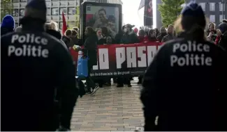  ?? ?? Police look on as demonstrat­ors hold a banner outside the National Conservati­sm conference in Brussels