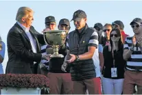  ?? JULIO CORTEZ/THE ASSOCIATED PRESS ?? President Donald Trump, left, presents the winner’s trophy to U.S. Team Captain Steve Stricker on Sunday after the final round of the Presidents Cup golf tournament at Liberty National Golf Club in Jersey City, N.J.