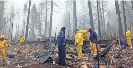  ??  ?? After a brief delay to let a downpour pass, volunteers resume their search for human remains at a mobile home park in Paradise, Calif., on Friday. Fire officials fear the death toll from the Camp Fire will climb.