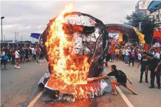  ??  ?? Activists burn an effigy of Duterte while he delivers his State of the Nation address at the House of Representa­tives in Quezon, Metro Manila, on Monday.