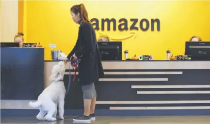  ?? Photos by Elaine Thompson, The Associated Press ?? An Amazon employee gives her dog a biscuit last week as the pair head into the Seattle company’s headquarte­rs. Among the perks for Amazon employees is that dogs are welcome in the building.