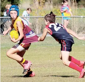  ??  ?? Above: Drouin Maroon’s Bodhi Pitt looks to dish off a handball as his Koo Wee Rup opponent grabs his guernsey in the under 12 game at Bellbird Park.