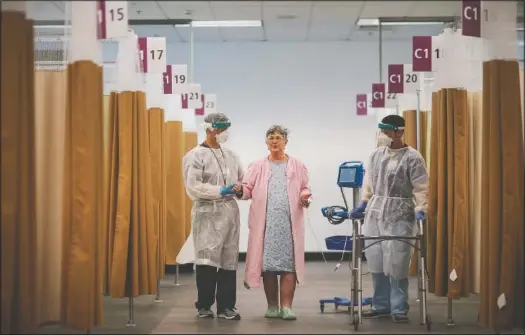  ??  ?? Patient Kathleen Feeney, 79, works with physical therapist Chris Collard (left) and registered nurse Edward Rojas at a field hospital in Cranston, R.I. (AP Photo/David Goldman)