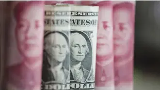  ?? —AFP ?? BEIJING: Chinese 100 yuan notes and one US dollar notes in Beijing. China just raised the exchange rate for the yuan against the US dollar by 0.92 percent from the previous day, the biggest one-day increase in more than 11 years.