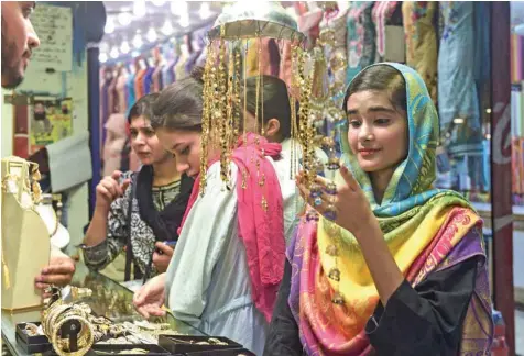  ?? — AFP ?? Girls shop at a market in Lahore, Pakistan, on Wednesday as they prepare to celebrate Eid al Fitr.