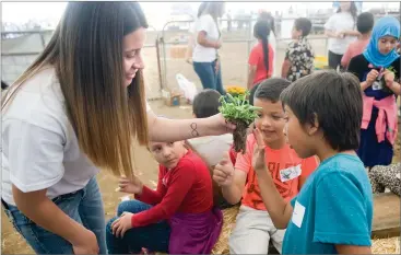  ?? RECORDER PHOTOS BY CHIEKO HARA ?? Monache High School FFA member Hope Flores, left, shows how to 'tickle the toes' for the best replanting tactics Friday, May 11, during Farm Day at the Portervill­e Fair. About 1,500 local second-graders visit at least nine stations to learn about...