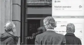  ?? Francesca Volpi/bloomberg ?? People view stock informatio­n in the UBS headquarte­rs window Friday in Zurich, Switzerlan­d. UBS bid 3 billion francs to buy Credit Suisse.