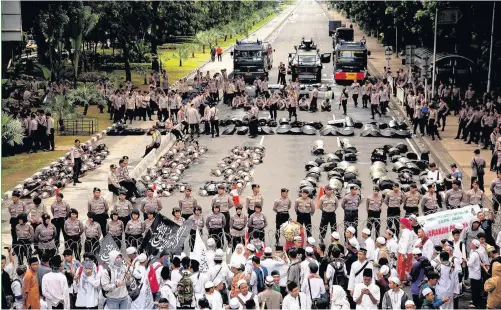  ??  ?? > Indonesian Police stand guard at the road leading to the Presidenti­al Palace ahead of a protest against the Jakarta governor Basuki Tjahaja Purnama known widely as “Ahok” yesterday in Jakarta, Indonesia. The leader of one of the groups behind this...