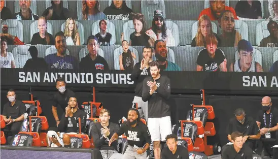  ?? KIM KLEMENT/AP ?? Virtual fans are displayed on a video board behind the Spurs bench in the first half against the Kings on Friday.