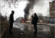  ?? YEVHEN TITOV / AP ?? Local residents talk against the background of a building burning after the Russian shelling in the town of Chasiv Yar on Monday.