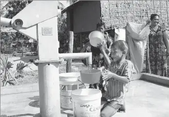  ?? ZHANG ZHAO / XINHUA ?? Children fetch water from a new well constructe­d under the Phase II of China-aided rural water supply and road projects in Kampong Speu province of Cambodia.