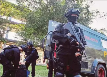  ?? REUTERS PIC ?? An anti-terrorism policeman holding a rifle as others seized crude bombs at the Riau University building in Pekanbaru, Sumatra, on Saturday.