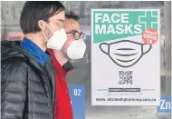  ?? AFP ?? People wearing face masks walk past a sign advertisin­g them in Melbourne, Australia yesterday.