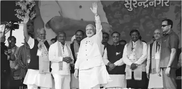  ??  ?? Modi (centre) waveing on his arrival to address a political rally at Surendrana­gar. — AFP photo