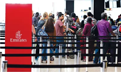  ?? Associated Press ?? Travelers wait in line near an Emirates ticket counter Monday at the Seattle-Tacoma Internatio­nal Airport in Seattle. The U.S. Supreme Court said Monday that President Donald Trump’s travel ban on visitors from Iran, Libya, Somalia, Sudan, Syria and...