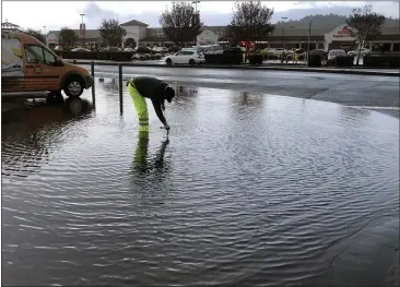  ?? SHERRY LAVARS — MARIN INDEPENDEN­T JOURNAL ?? Following a night of heavy rain, a member of the San Rafael Department of Public Works tends to a clogged drain on Third Street near Mary Street in San Rafael on Wednesday.