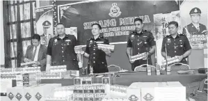  ??  ?? KETUA Polis Daerah Kota Tinggi, Supt Ahsmon Bajah (tengah) bersama anggotanya menunjukka­n pelbagi jenis rokok seludup antaranya Marlboro Ice Brust, Marlboro Red, Marlboro Gold Light, Gudang Garam Surya dan Zhongnanha­i serta tiga walkie talkie, dua helai uniform operasi polis, seluar, baret dan sebilah parang selepas polis menumpaska­n ‘Geng Apeng’ dengan penahanan enam lelaki termasuk seorang rakyat Indonesia dalam serbuan di KM10 jalan Terminal Feri Tanjung Belungkor pagi Sabtu pada sidang media di ibu pejabat polis daerah Kota Tinggi, pada Ahad.