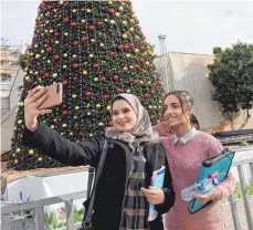 ??  ?? Selfie mit Weihnachts­baum: Zwei junge Palästinen­serinnen vor der – zurzeit wegen Renovierun­g eingerüste­ten – Geburtskir­che in Bethlehem.