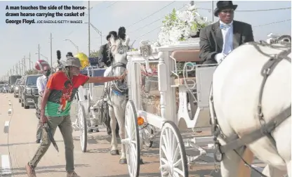  ?? JOE RAEDLE/GETTY IMAGES ?? A man touches the side of the horsedrawn hearse carrying the casket of George Floyd.