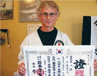  ??  ?? Gilles Savoie avec son certificat de 8e dan qui fait de lui un Grand Maître en taekwondo. - Acadie Nouvelle: Robert Lagacé