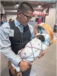  ??  ?? Nick Nez of Chinle proudly carries his 10-day-old son Lander Blue Nez at the Jehovah’s Witnesses convention Friday in Phoenix.