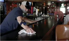  ??  ?? Greg Anderson wipes down the bar on the first day Tuner’s Bar and Grill has reopened after being closed in St Charles, Missouri. Photograph: Jeff Roberson/AP