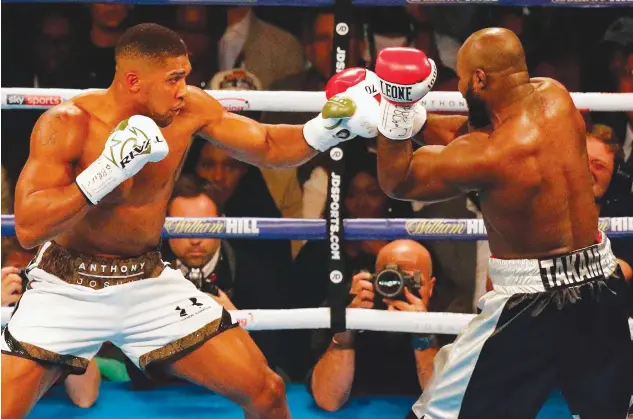  ??  ?? Anthony Joshua throws a punch at Carlos Takam during their bruising world heavyweigh­t title fight in Cardiff on Saturday night. (AFP)