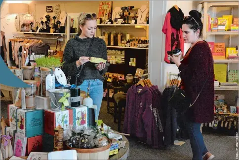  ??  ?? Natalia Wiese, left, of Niantic, and her cousin Cayla Fresquez, of Norwich, browse at Hang the Moon last week in downtown Mystic.