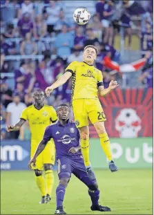  ?? [JOHN RAOUX/THE ASSOCIATED PRESS] ?? Crew SC’s Wil Trapp heads the ball away from Orlando City’s Carlos Rivas in Saturday’s first half in Orlando.