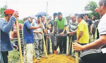  ??  ?? Villagers and family members putting the cross at Florancesi­a’s grave at the Seventh Day Adventist Church, Kampung Ampungan. — Photo by Wilfred Pilo