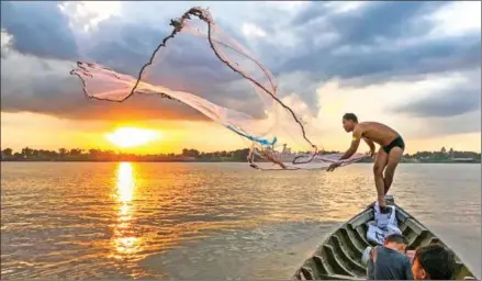  ?? HONG MENEA ?? A fisherman throws his fishing net into the Mekong River in Kohdach commune of Phnom Penh’s Chroy Changvar district in 2020.