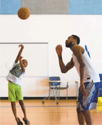  ?? ALGERINA PERNA/BALTIMORE SUN ?? Former Lake Clifton star Will Barton works with Taj Womack, 8, at his his annual skills camp at Waverly Middle School on Thursday. Barton said he wants to show kids in Baltimore “you can make it out of here and people can have success and still come back.”