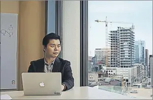  ?? CP PHOTO ?? Hai Hu, CEO and co-founder of Orgrimmar Inc., poses in his office in a Halifax office tower with cranes from the constructi­on boom visible in the background.