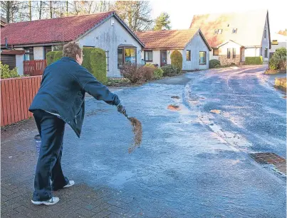  ?? Picture: Steven Brown. ?? A Glenrothes resident gritting a path so she can go shopping.