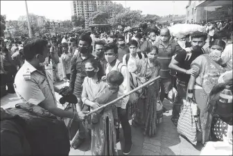  ?? RAFIQ MAQBOOL / ASSOCIATED PRESS ?? A police officer keeps crowds under control at Mumbai’s Lokmanya Tilak Terminus on Wednesday. Health officials are worried by a lack of social distancing in India’s big cities.