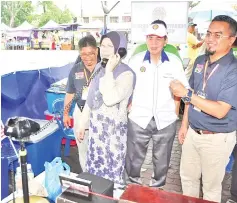  ??  ?? Hamisa holding an antique telephone at the PKMT exhibition booth that displayed historical items as PKMT president OKK Hj Mohd Ayub Kee Abu Bakar (second right) and Ismail look on.