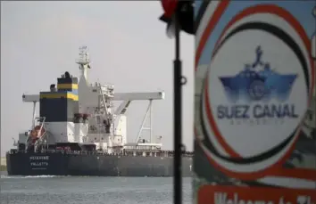  ?? Ayman Aref/Associated Press ?? A cargo ship sails through the town of Ismailia, Egypt, on Tuesday as traffic resumed through the Suez Canal after being blocked by a massive container ship that had been stuck sideways for nearly a week.