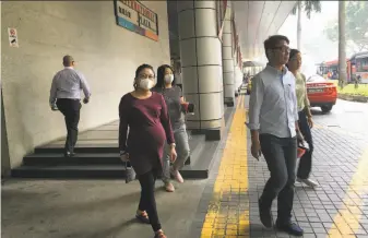  ?? Wong Maye-E / Associated Press ?? Singapore office workers wear masks in August to protect themselves from hazy weather after winds blew smoke from fires in Indonesia to the city-state and southern Malaysia.