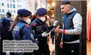  ?? ?? Police officers check the vaccinatio­n status of visitors during a patrol on a Christmas market in Vienna, Austria